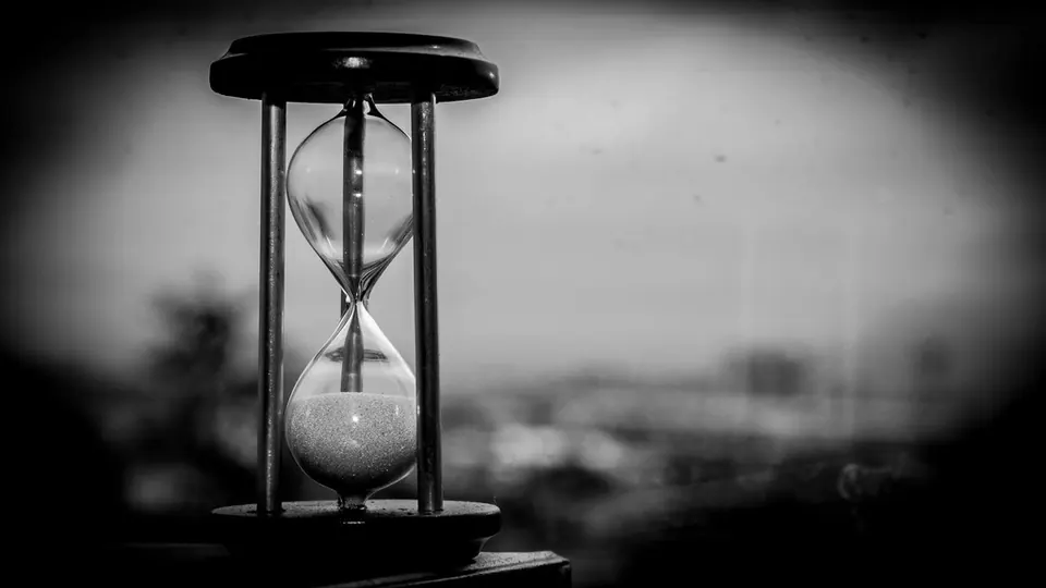 Hourglass with sand running through, in black and white