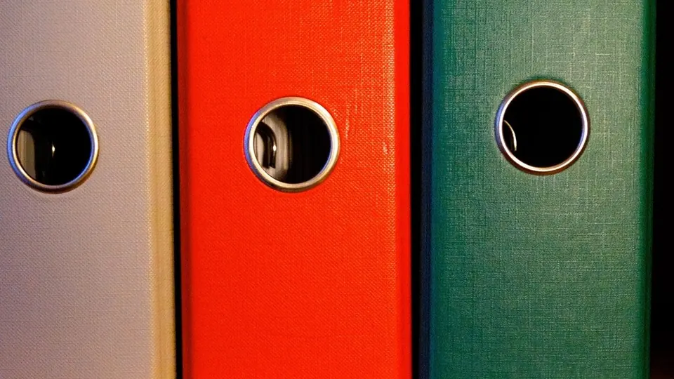 Grey, red and green ring binders on a shelf